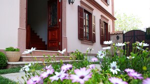 Un bâtiment avec un escalier menant à une porte, un pot de fleurs et un jardin fleuri.