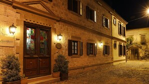 Un bâtiment historique à la façade en pierre, doté de volets en bois et situé dans une rue pavée.