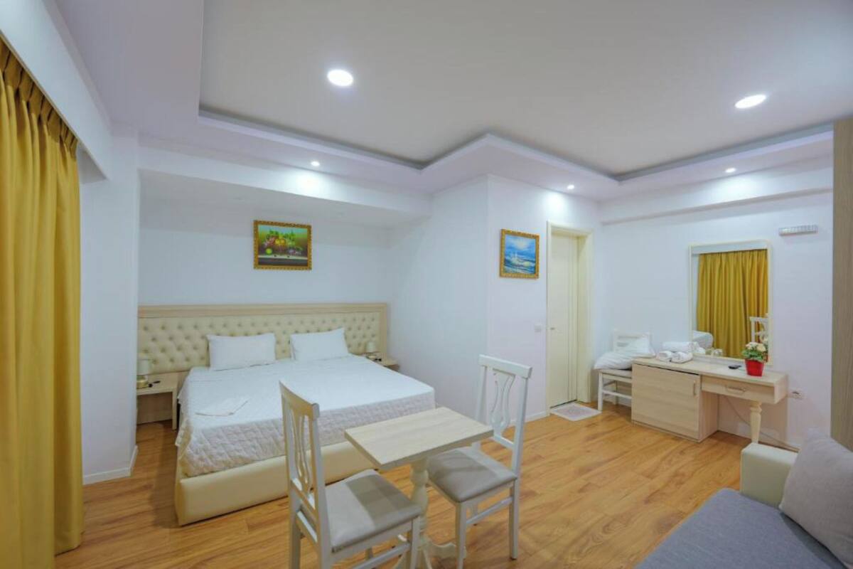 A hotel room with a bed, desk, chair, and a small table.