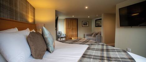 A hotel room with two beds, a television, a wooden headboard, and a door leading to another room.