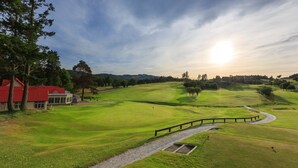 Un campo de golf con un edificio de techo rojo, una valla de madera y un cielo despejado.