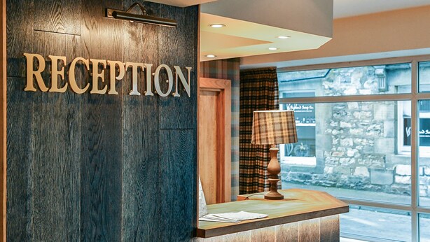 Una mesa de recepción con un cartel que dice "RECEPTION" y una lámpara en la encimera.