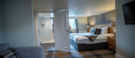 A modern bedroom with a large bed, bedside tables, a wooden bench, and a view of the bathroom.