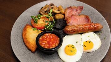 A plate of breakfast food including eggs, sausages, mushrooms, tomatoes, beans, and toast.