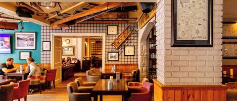 A cozy restaurant with wooden tables and chairs, a brick wall with a map, and a staircase leading to another area.