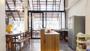 A modern cafe with wooden furniture, a central island, and a view through large windows. - Boon Street Hostel (Bangkok)