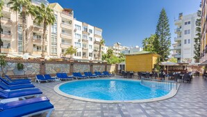A swimming pool with lounge chairs, surrounded by a stone wall and palm trees. - Wasa Hotel (Alanya)