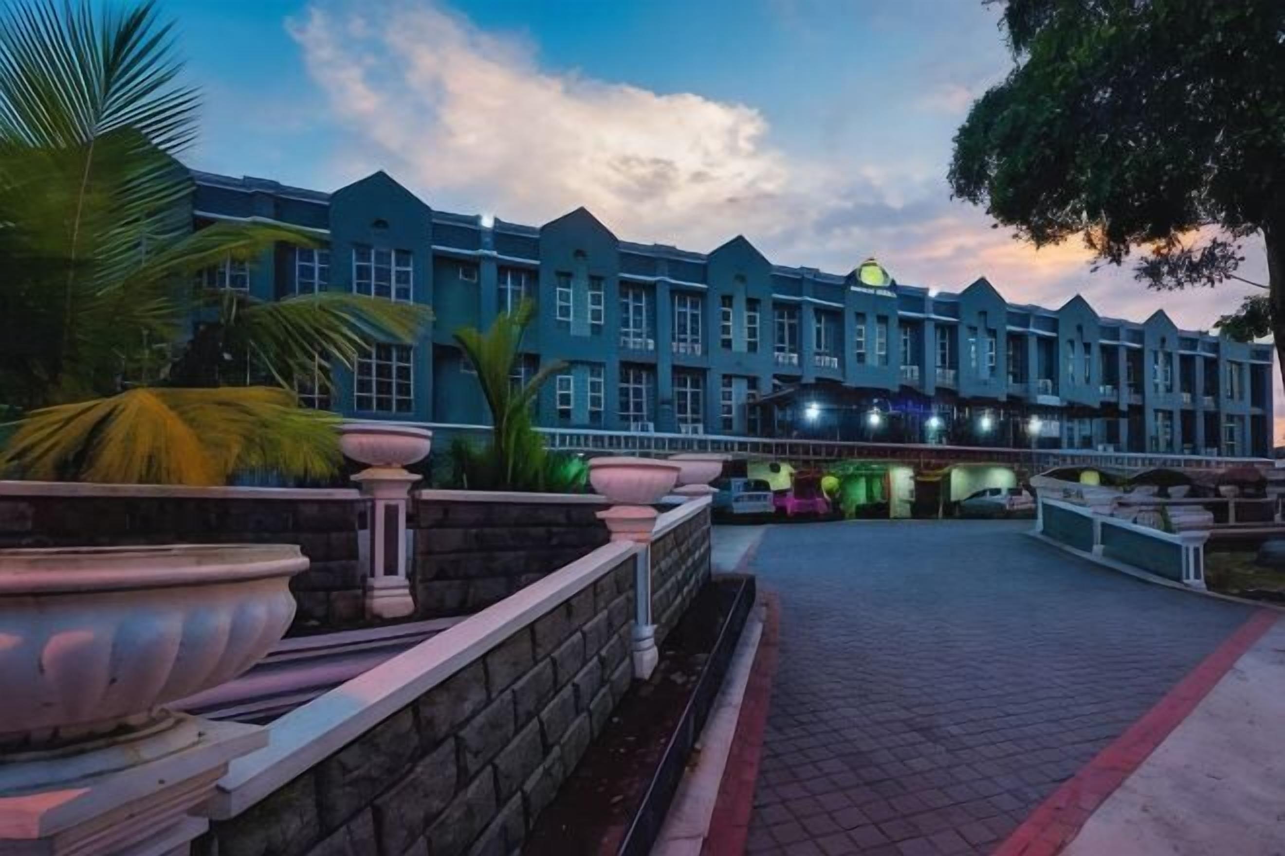 A hotel with a row of rooms, a stone wall, and a paved walkway.