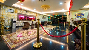 Een hotel lobby met een receptiebalie, zithoek en een decoratief vloerkleed.