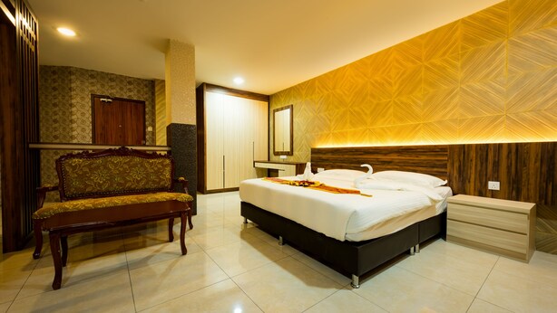 Een hotelkamer met een bed, een bankje, een dressoir en een spiegel.