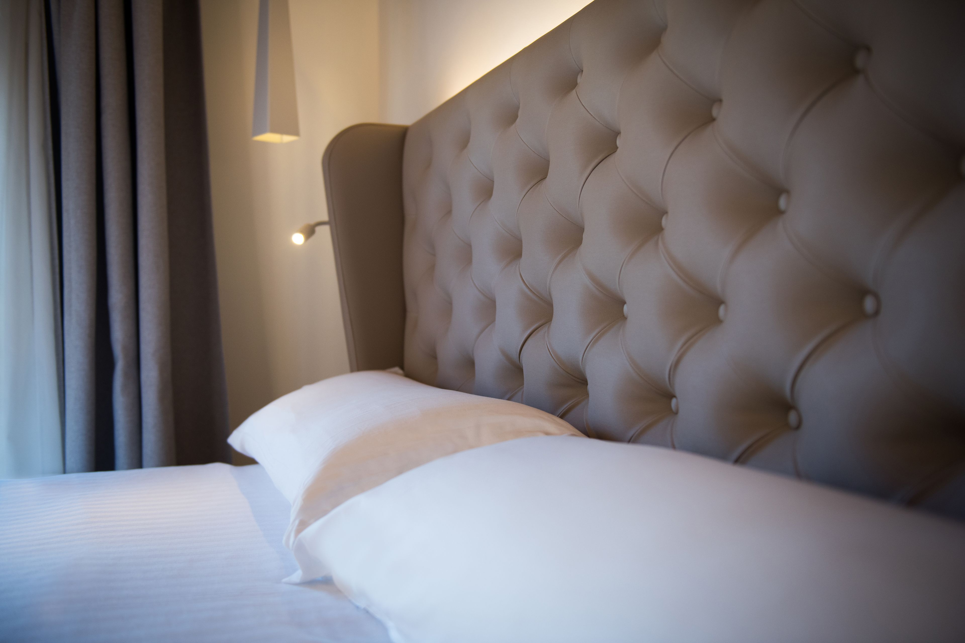 Un lit avec une tête de lit capitonnée et du linge de lit blanc.