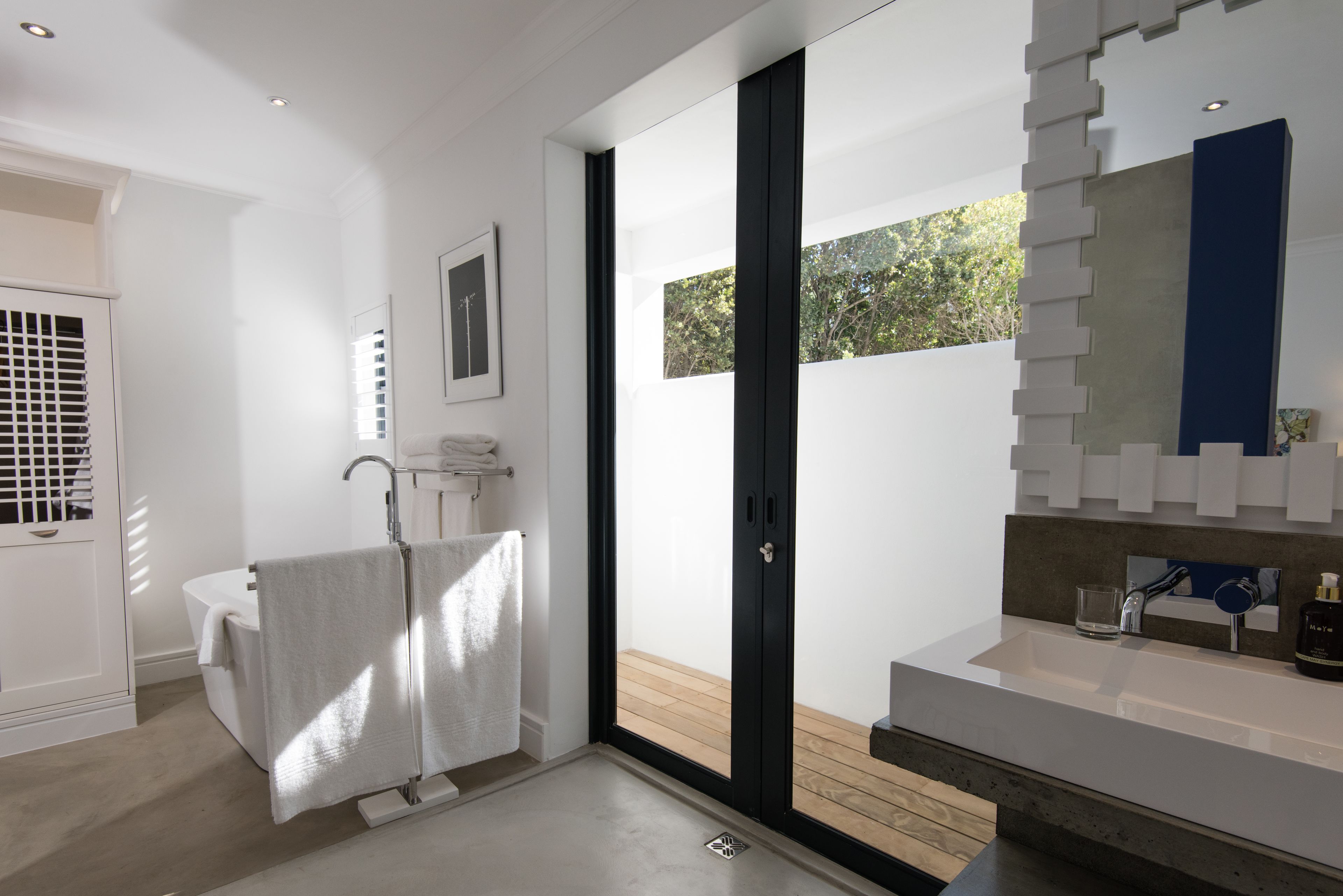 Ein modernes Badezimmer mit einer Badewanne, einem großen Spiegel und einem Waschbecken.