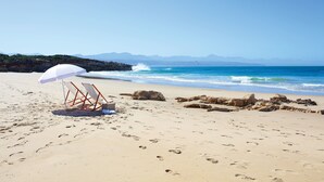 A beach with footprints, a white umbrella, and a chair. - The Old Rectory (Plettenberg Bay)