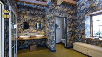 A bathroom with a large mirror, two sinks, and a bench.