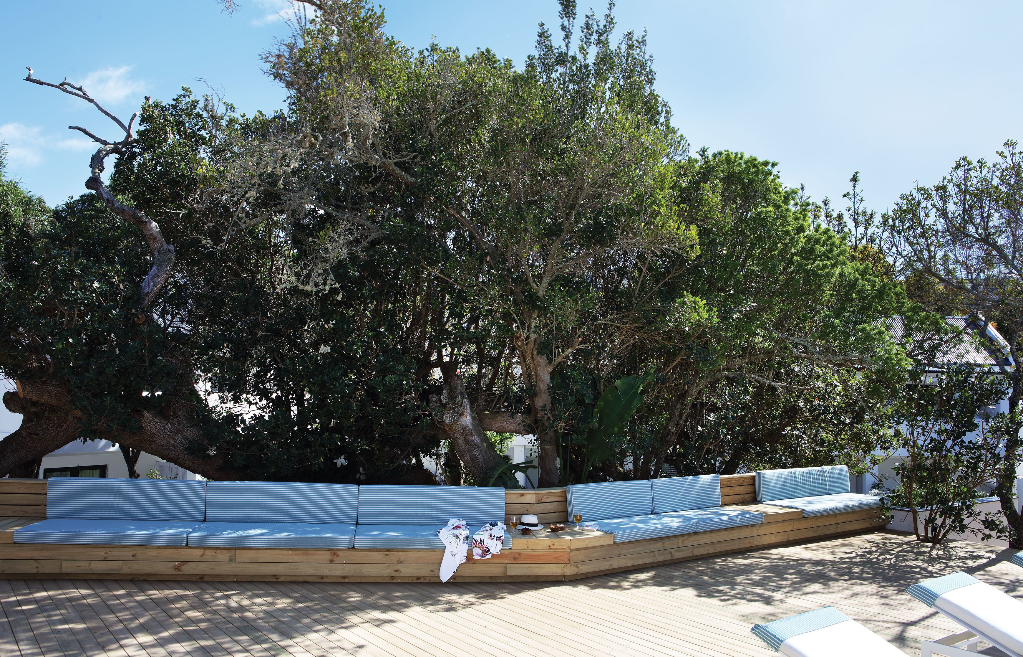 A wooden deck with a built-in seating area, surrounded by trees.