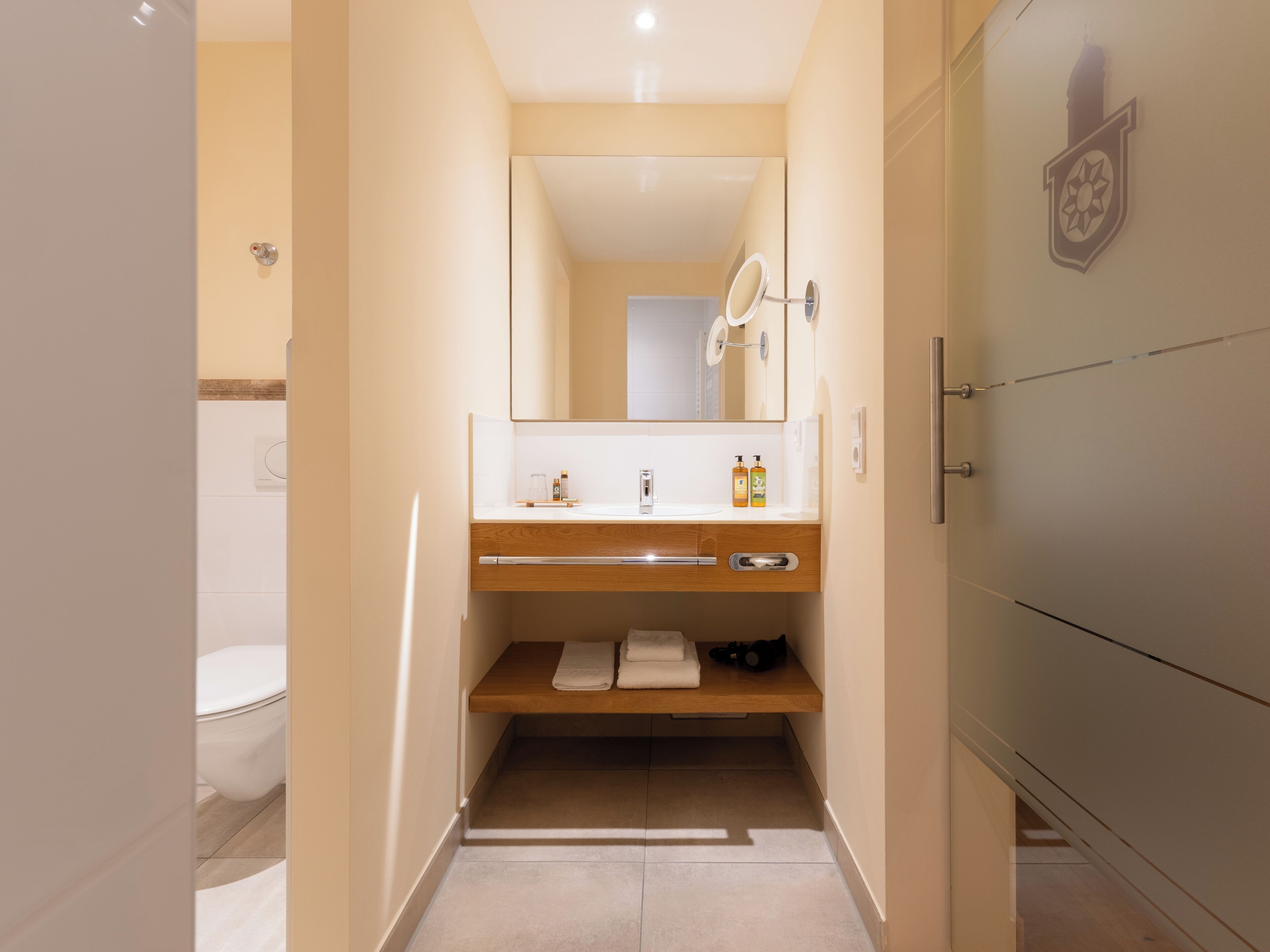 A modern bathroom with a wooden vanity, a mirror, and a towel rack.