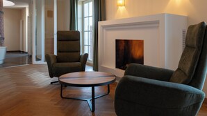 A modern living room with a fireplace, two armchairs, and a round coffee table. - Schlossgut Odelzhausen (Odelzhausen)
