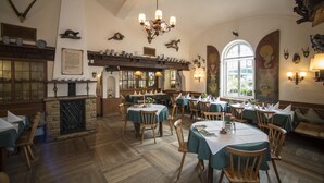 A dining area with wooden tables and chairs, a fireplace, and various wall decorations including animal heads and a mural. - Schlossgut Odelzhausen (Odelzhausen)