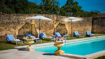 Una piscina al aire libre de temporada, sombrillas