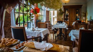 A restaurant with multiple tables, chairs, and a variety of pastries and bread displayed on a counter. - Domaine de La Groirie - Le Mans Ouest (Trange)