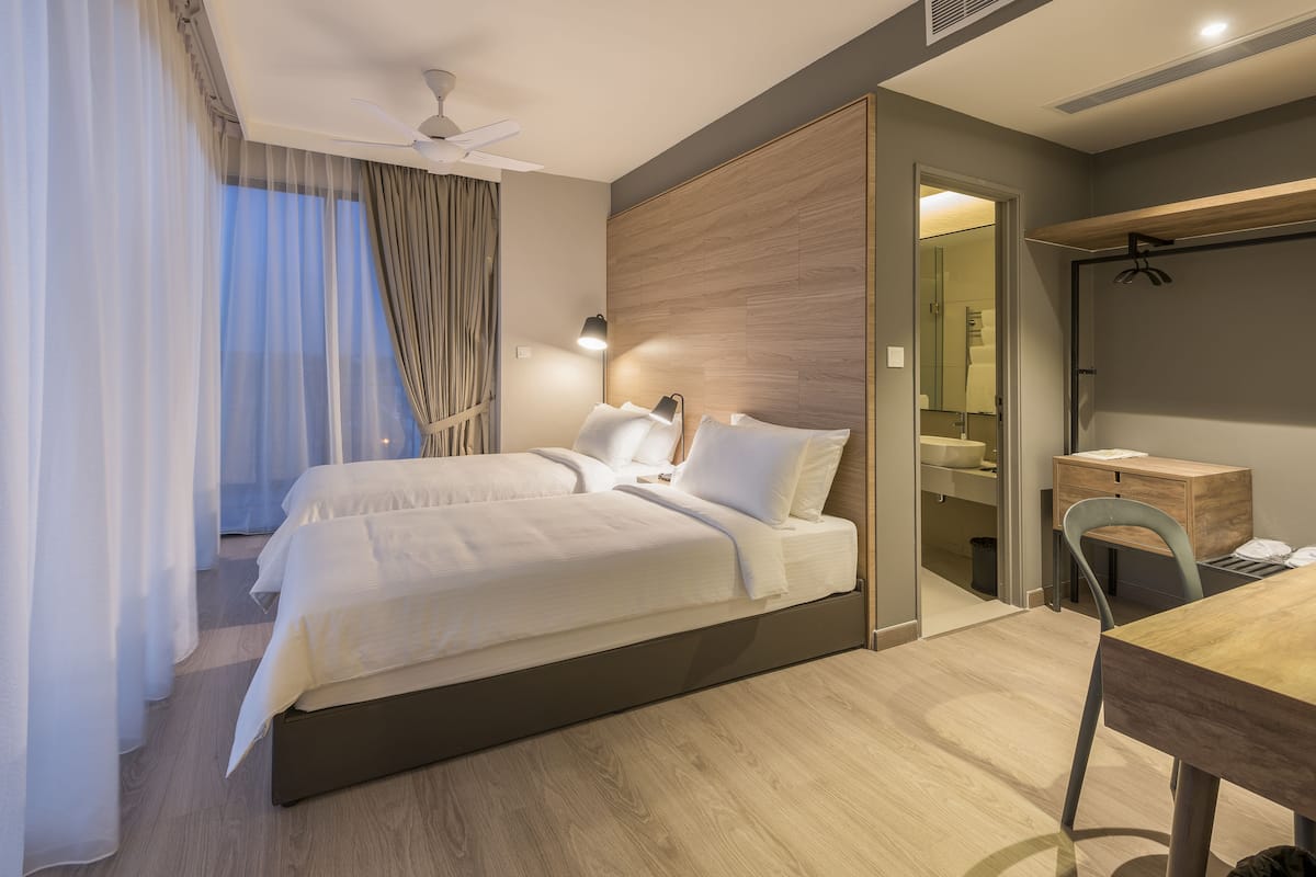 A modern hotel room with a large bed, a desk, and a wardrobe.