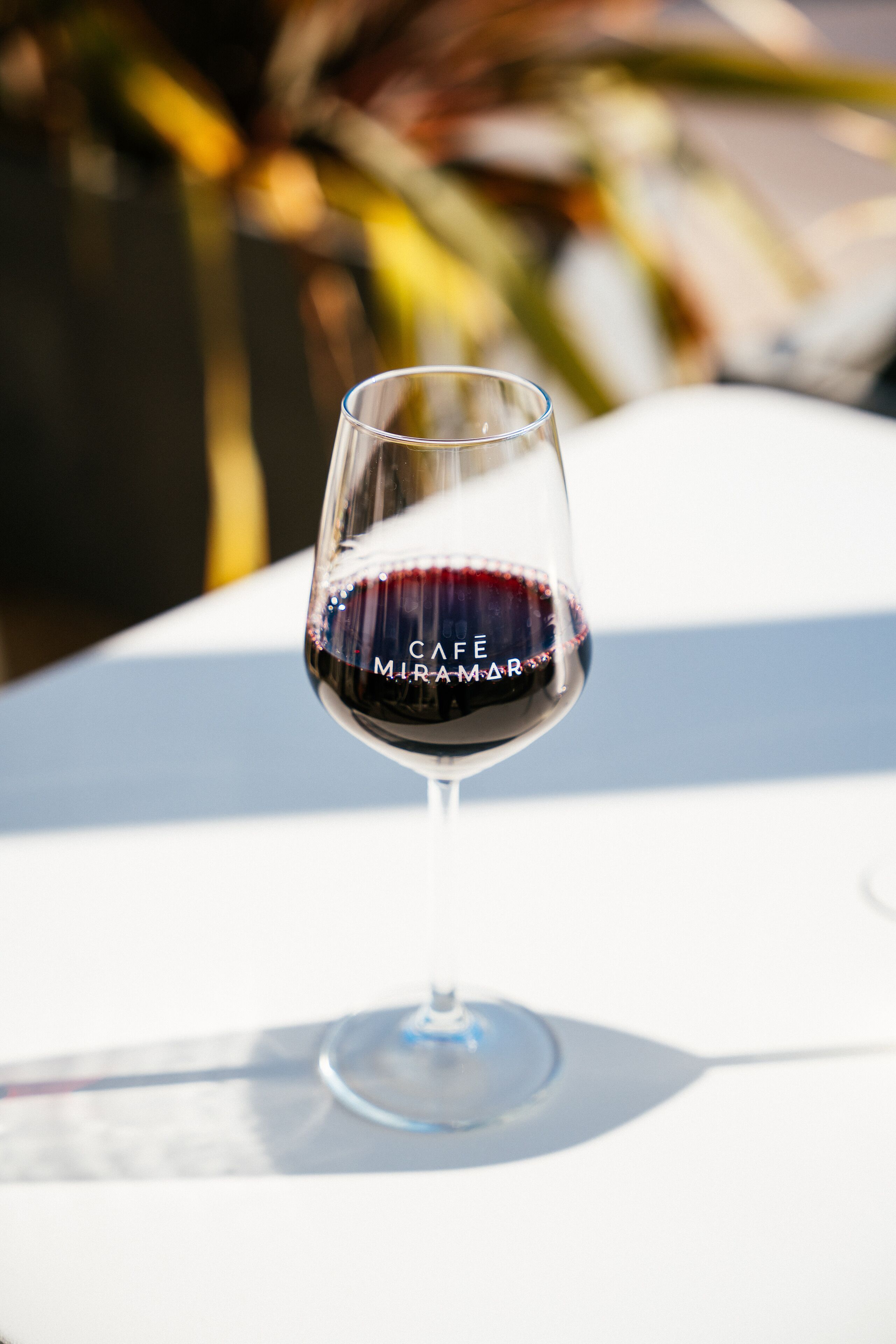 Una copa de vino con una etiqueta sobre una mesa blanca.