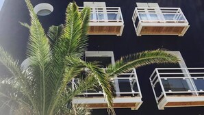 A modern building with multiple balconies and a dark facade. - Hôtel Café Miramar (Le Grau-Du-Roi)