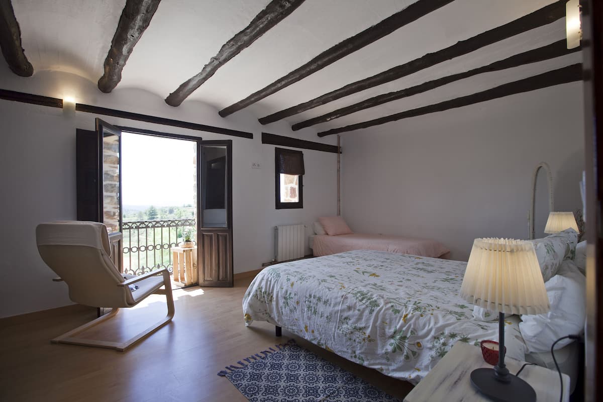 Une chambre à coucher avec un lit, une chaise, une lampe et une vue sur l’extérieur.