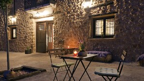 Un edificio de piedra con una mesa y sillas de madera, una planta en maceta y una vela sobre la mesa.