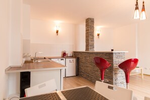 A modern kitchen with a central island, a built-in stove, and a stone accent wall. - Spacious Ultracentral Apartment Old City (Bucharest)