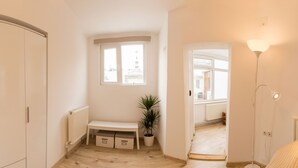 A bright, minimalist room with a large window, a radiator, a bench, a potted plant, and a lamp. - Spacious Ultracentral Apartment Old City (Bucharest)