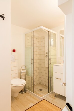 A modern bathroom with a glass shower enclosure, a toilet, and a vanity with a mirror. - Spacious Ultracentral Apartment Old City (Bucharest)