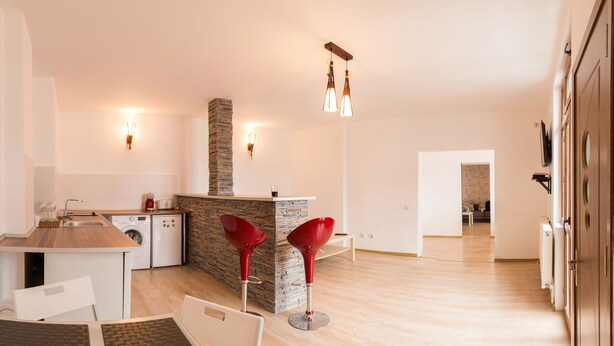 A modern kitchen with a central island, a dining area with a table and chairs, and a living space with a sofa and a TV. - Spacious Ultracentral Apartment Old City (Bucharest)