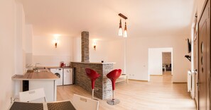 A modern kitchen with a central island, a dining area with a table and chairs, and a living space with a sofa and a TV. - Spacious Ultracentral Apartment Old City (Bucharest)