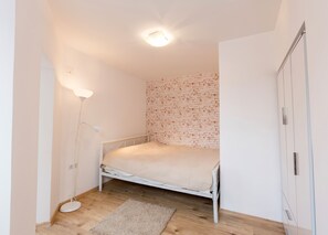 A small, neatly arranged bedroom with a single bed, a bedside lamp, a wardrobe, and a brick-patterned wall. - Spacious Ultracentral Apartment Old City (Bucharest)