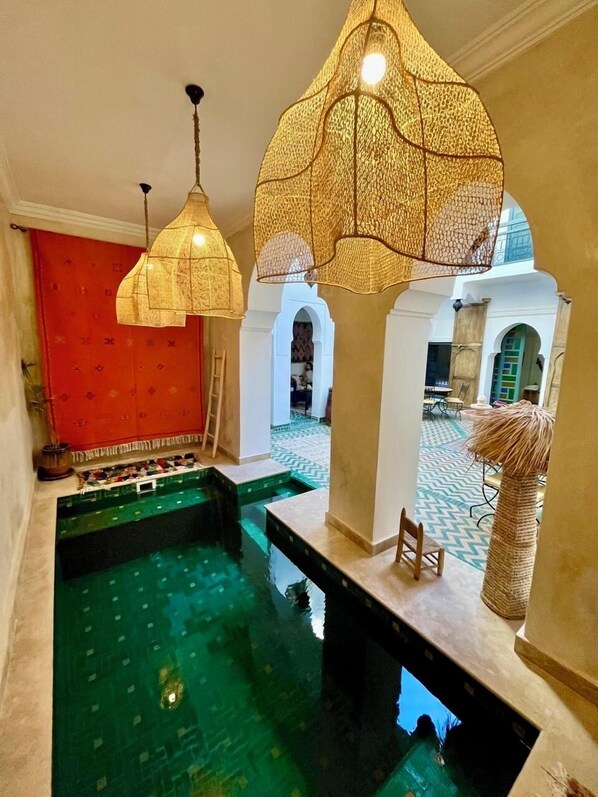 A pool area with a clear view of the surrounding architecture, including arches and a patterned floor. - Riad ECILA (Marrakech)