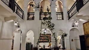 A spacious interior with a central fountain, multiple arches, and a patterned floor. - Riad Ecila (Marrakech)