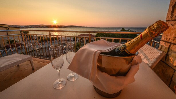 Un balcon avec une table dressée pour deux personnes, une bouteille de champagne et deux verres à vin.