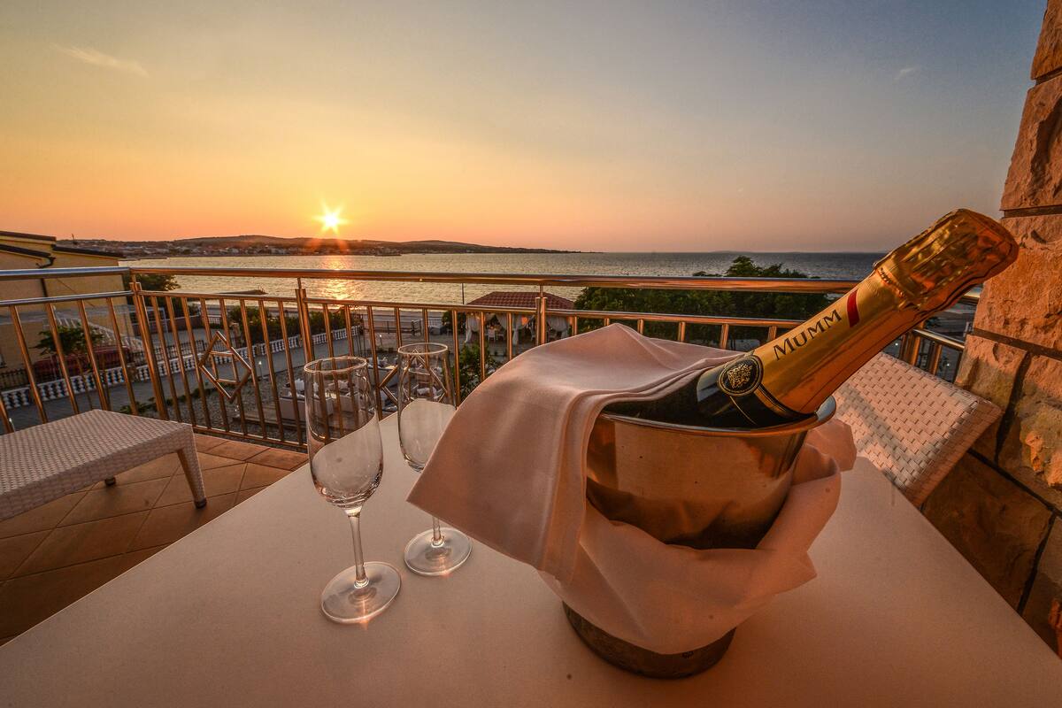 A balcony with a table set for two, a bottle of champagne, and two wine glasses.