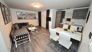 Un espace de vie compact comprenant un canapé, une table basse et un petit coin repas avec des chaises et une table.