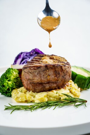 A steak with gravy, mashed potatoes, broccoli, and red cabbage on a white plate. - JH Villa (Unawatuna)