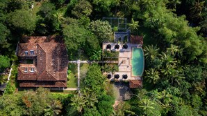 An aerial view of a property with a swimming pool, a tennis court, and lush greenery. - JH Villa (Unawatuna)