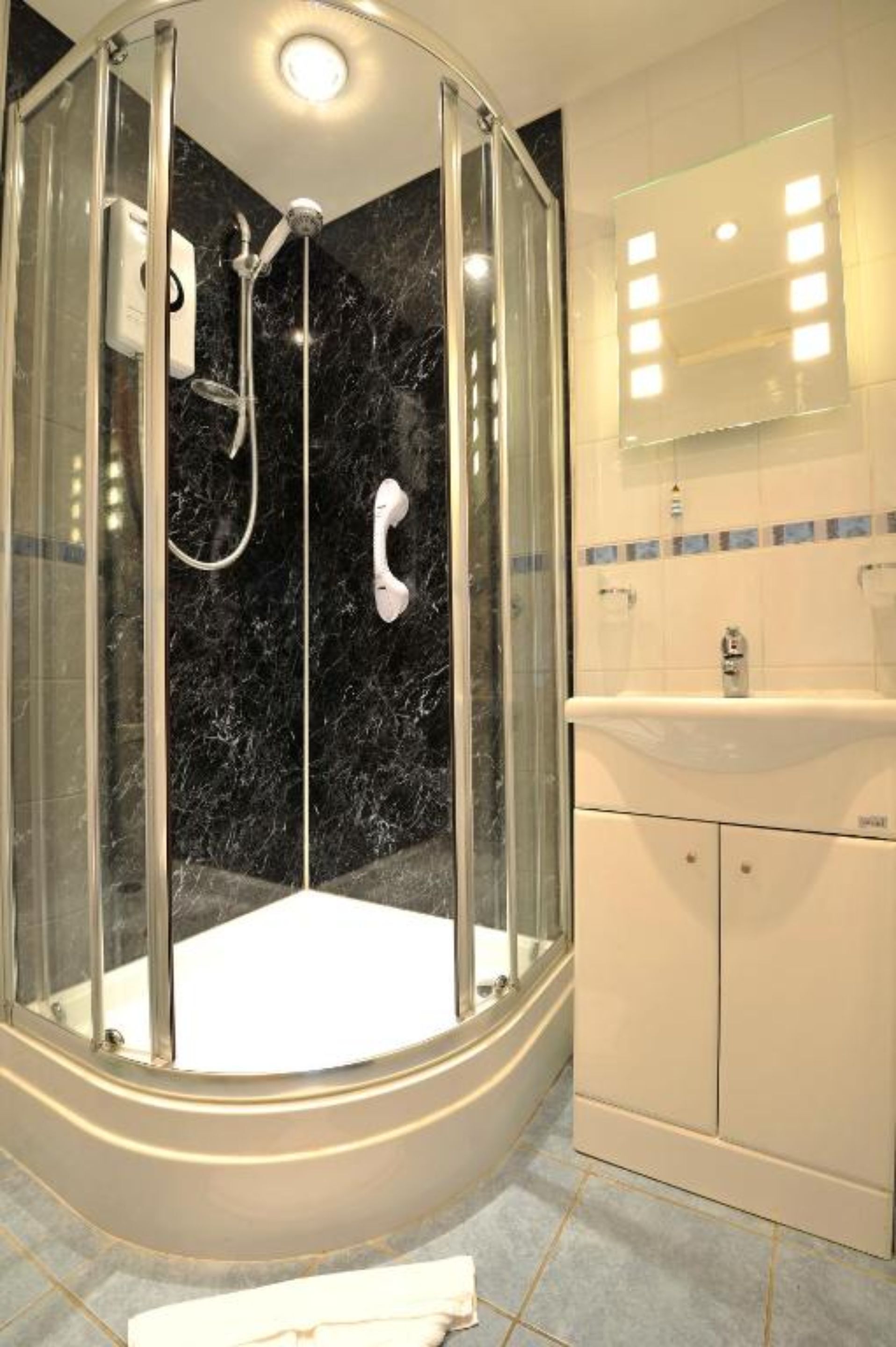 A modern bathroom with a glass-enclosed shower, a white sink, and a mirror above the sink.