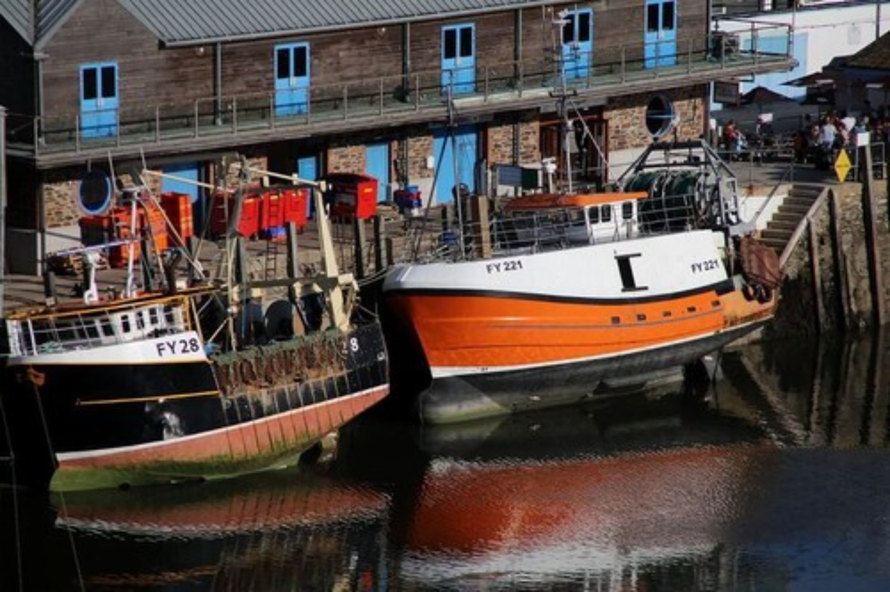 Two boats docked at a marina with a building in the background.