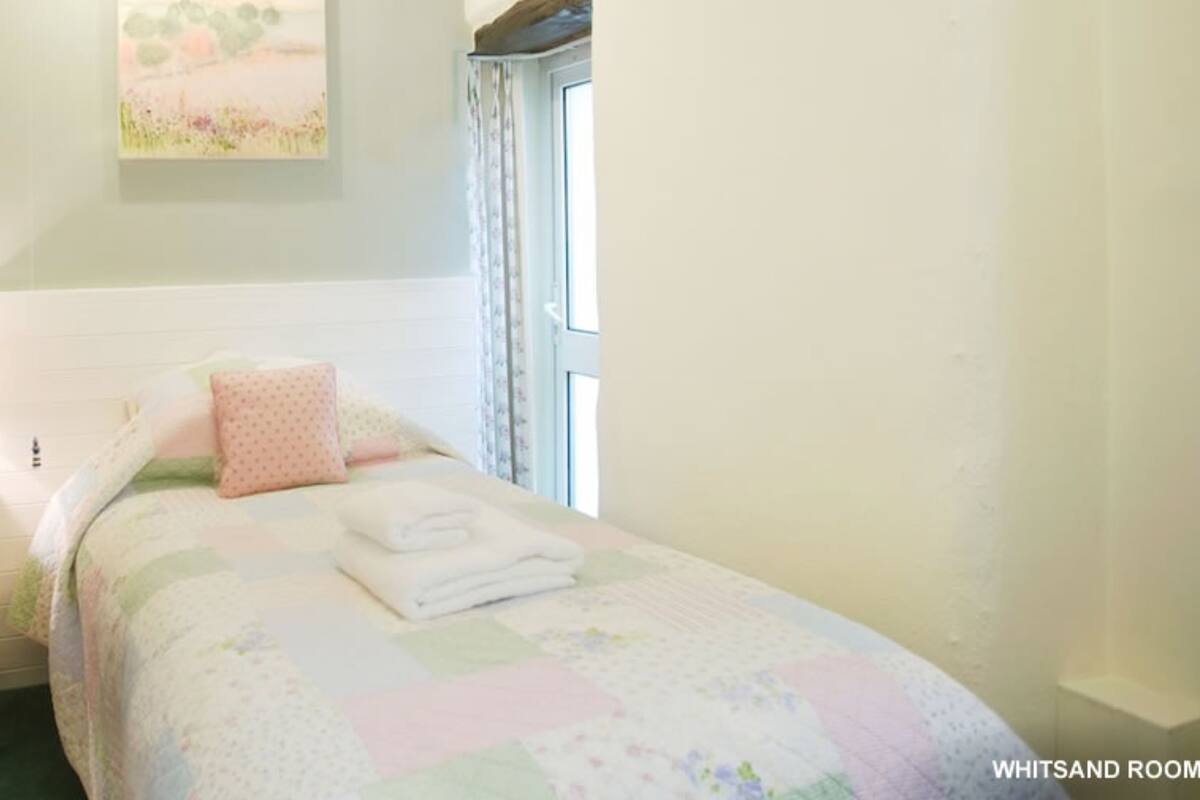Un dormitorio con una cama, una mesita de noche, una lámpara y un ventanal.