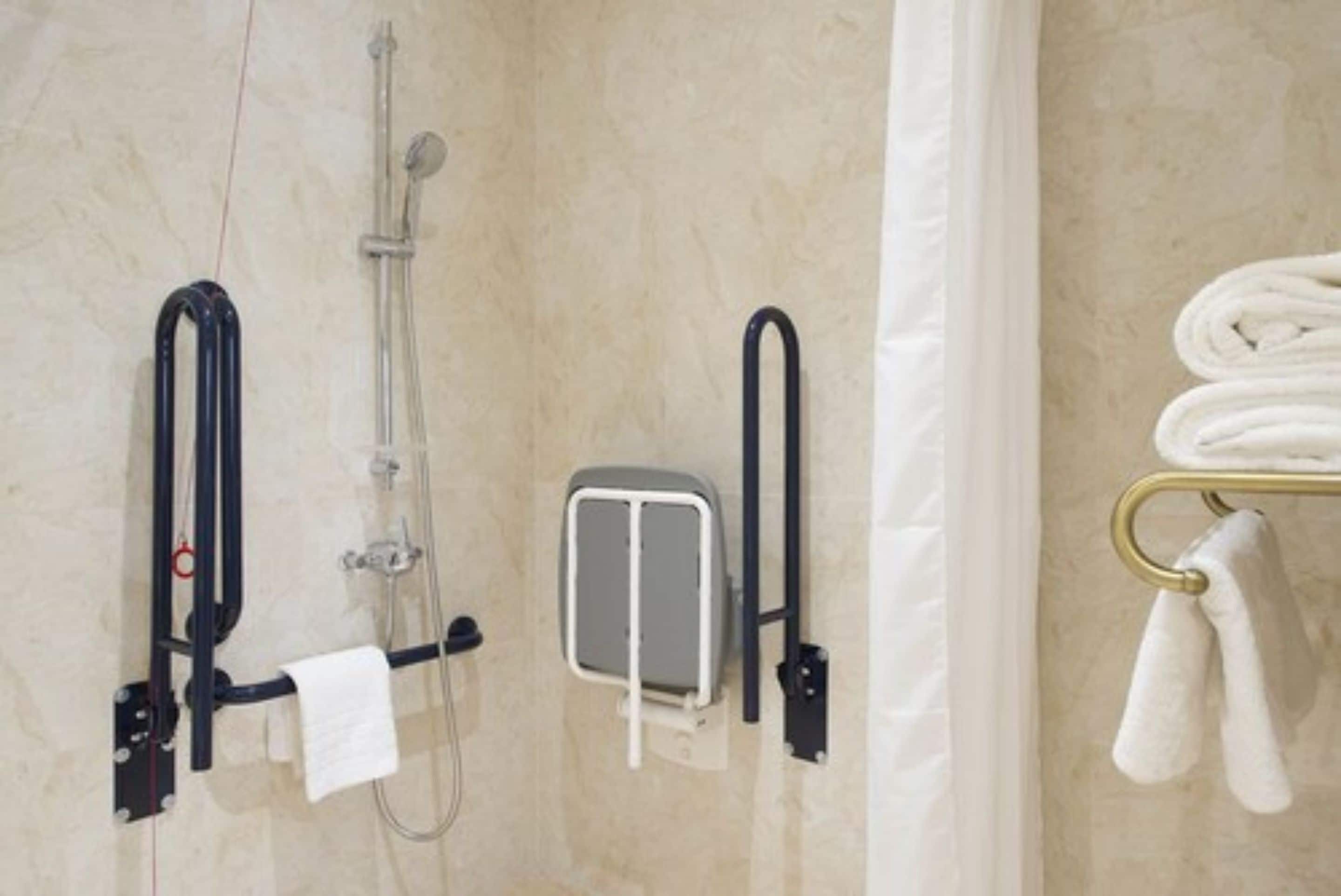 A bathroom with a shower, towel rack, and a towel dispenser.