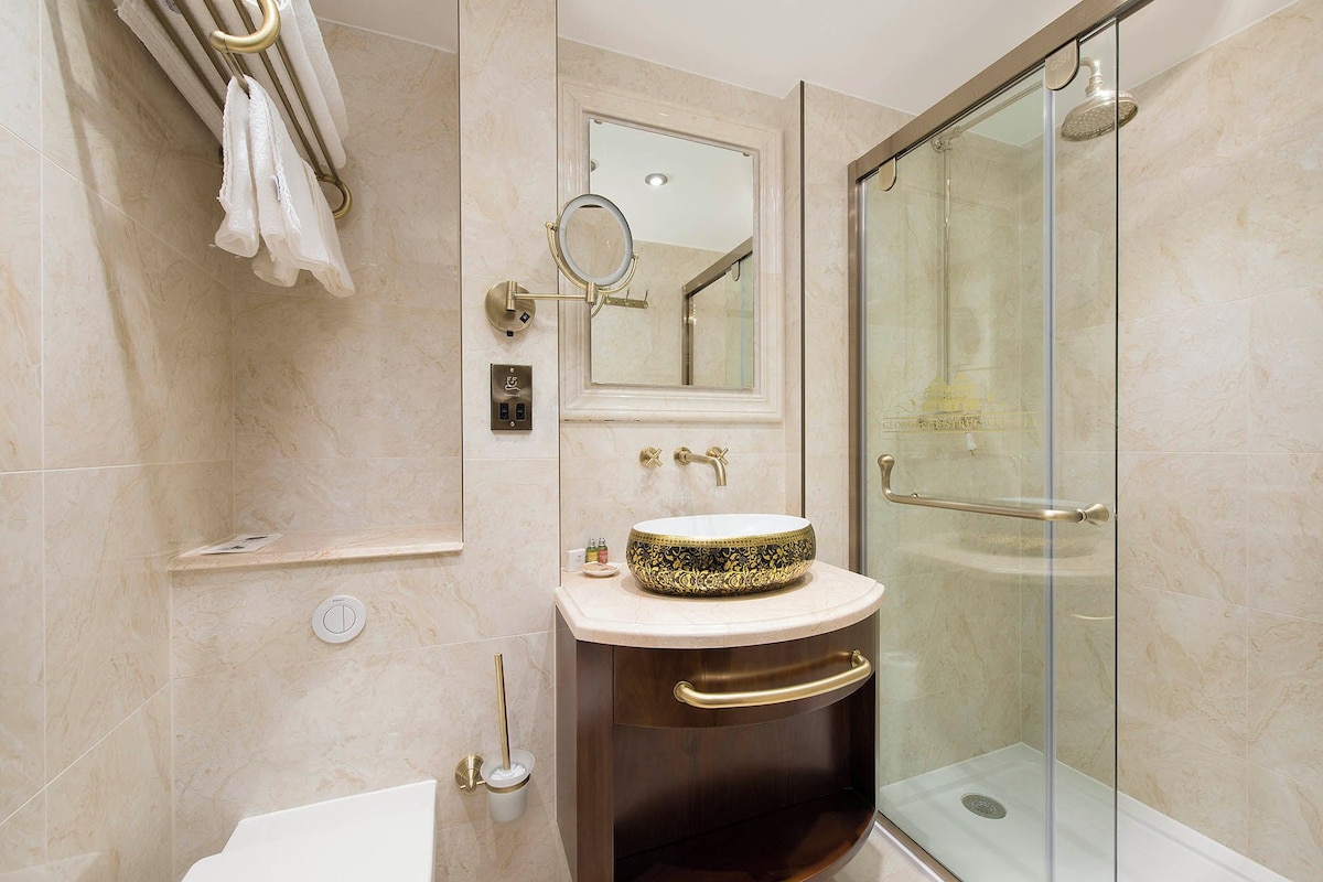 A modern bathroom with a glass shower enclosure, a vanity with a decorative bowl sink, and a towel rack with white towels.