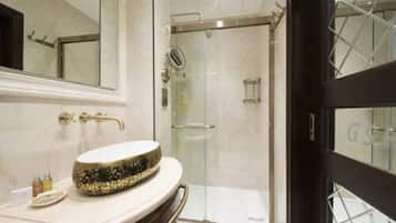 A modern bathroom with a round sink, a glass shower enclosure, and a large mirror.