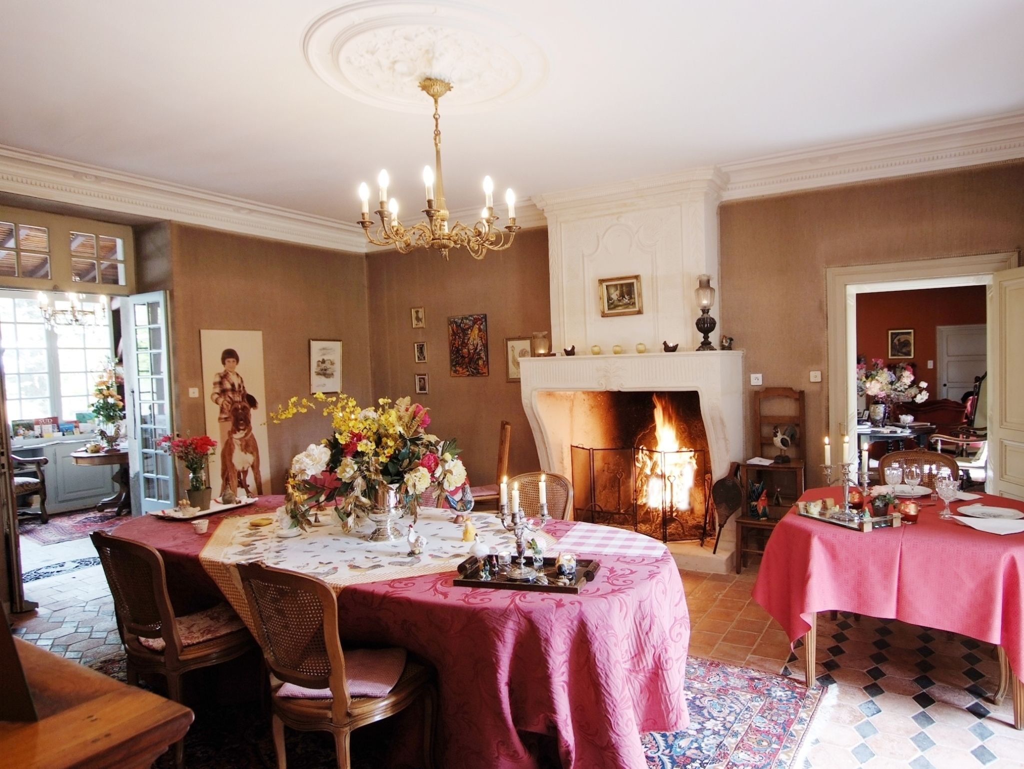 A dining room with a fireplace, a chandelier, and a table set for a meal.