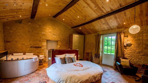 Un dormitorio acogedor con una cama grande, una bañera y una pared de piedra.